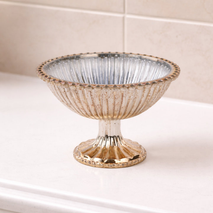 Decorative silver bowl on a white surface with a tiled wall background