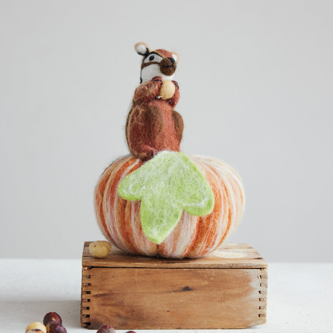 Decorative pumpkin with a raccoon figurine on top against a white background