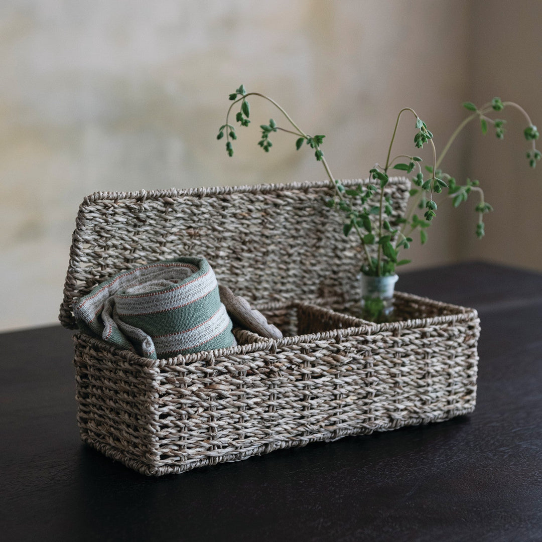 Woven basket with a striped towel and small plant on a dark surface