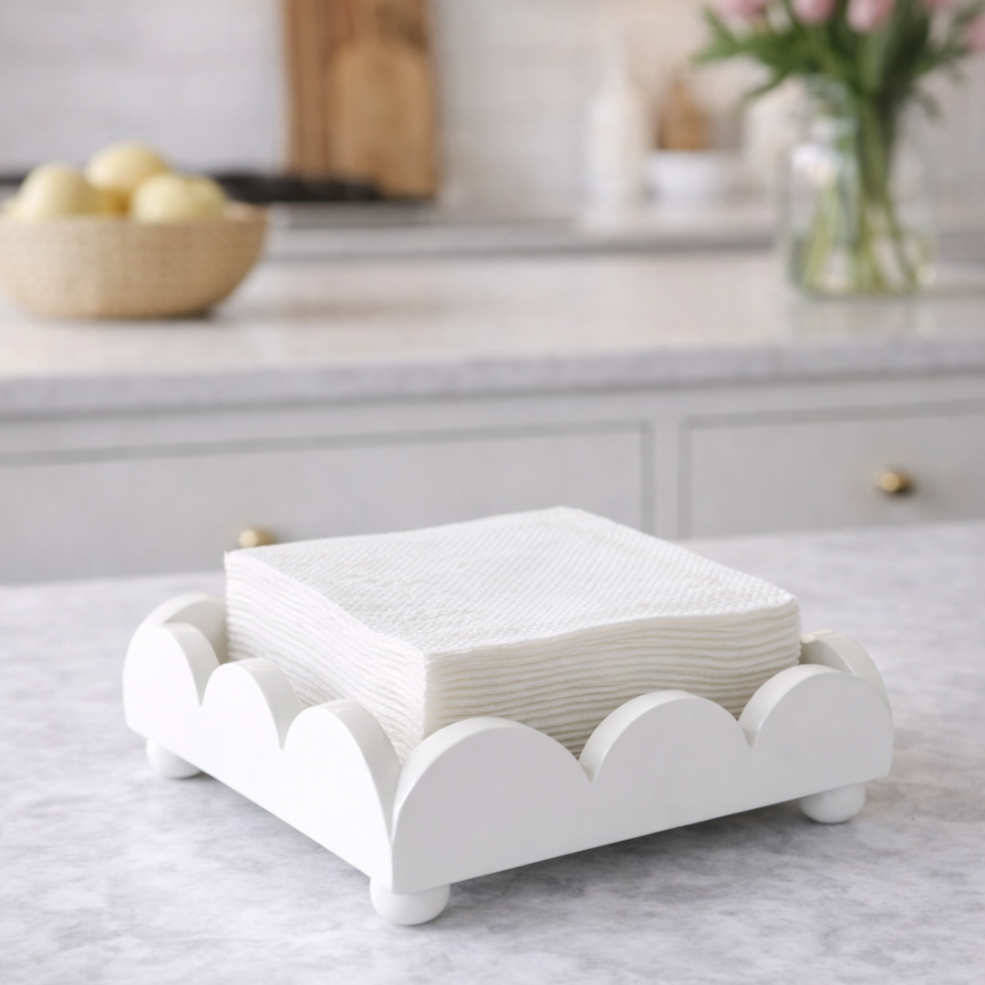 White napkin holder with folded white napkins on a marble countertop in a kitchen.