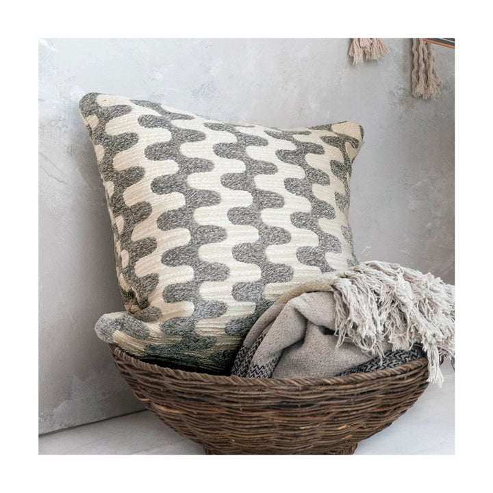 Decorative pillow with wavy pattern in a woven basket on a light background